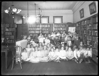 Ritratto di gruppo di bambini nella sala di lettura di una filiale non identificata della Queens Borough Public Library, c.1910