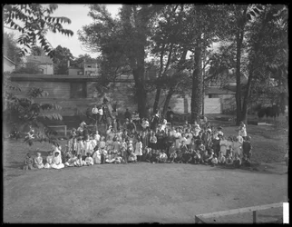 Grande gruppo di bambini riuniti per un ritratto di gruppo in un parco giochi non identificato, c.1910